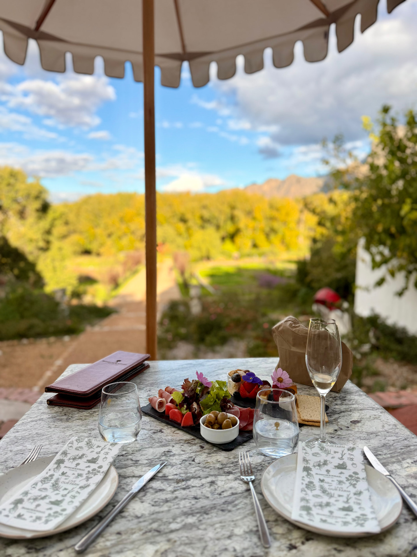 Farm lunch laid out on marble beneath a scalloped umbrella